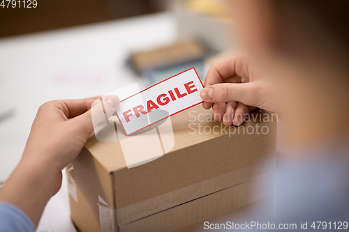 Image of woman sticking fragile mark to parcel box