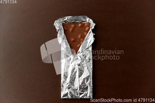 Image of milk chocolate bar with nuts in foil wrapper