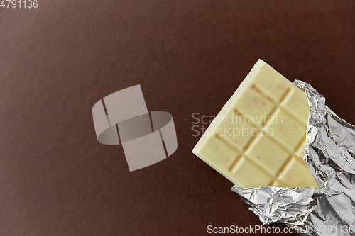 Image of white chocolate bar in foil wrapper on brown