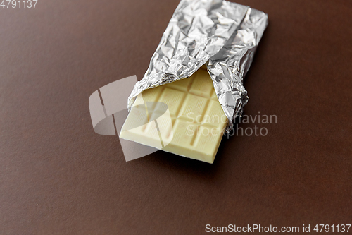 Image of white chocolate bar in foil wrapper on brown