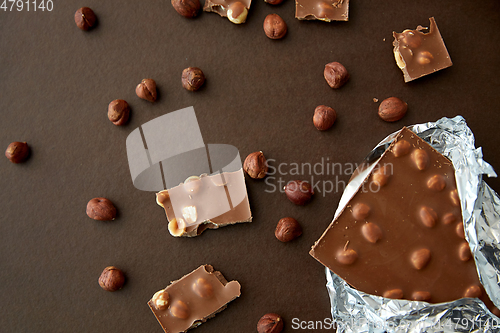 Image of milk chocolate bar with hazelnuts in foil wrapper