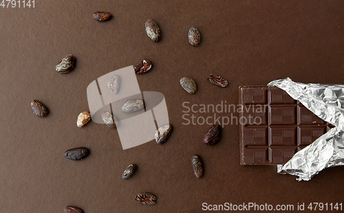 Image of dark chocolate bar in foil wrapper and cocoa beans