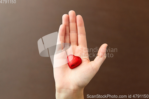 Image of hand with red heart shaped chocolate candy