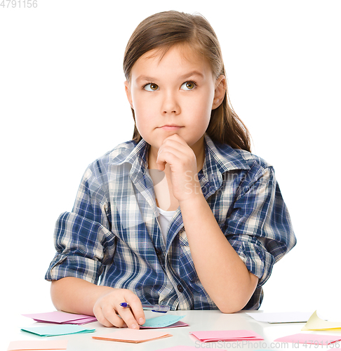 Image of Girl is writing on color stickers using pen