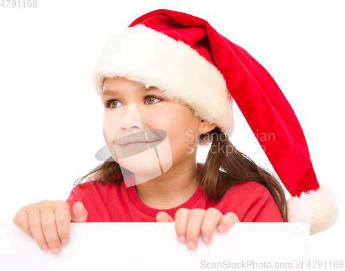 Image of Little girl in santa hat is holding blank board