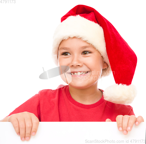 Image of Little girl in santa hat is holding blank board