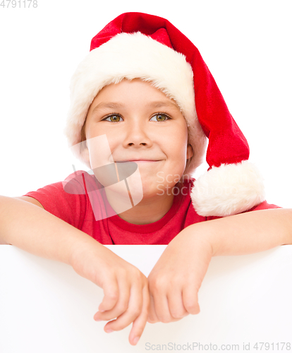 Image of Little girl in santa hat is holding blank board