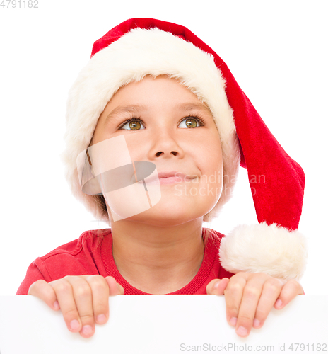 Image of Little girl in santa hat is holding blank board