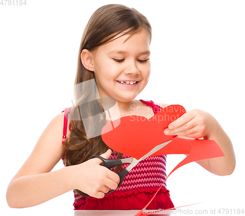 Image of Portrait of a little girl cutting out red heart