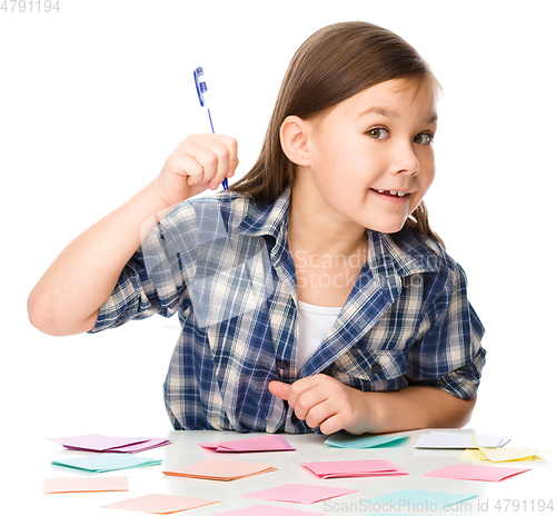 Image of Girl is writing on color stickers using pen
