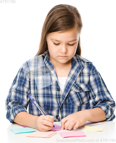 Image of Girl is writing on color stickers using pen