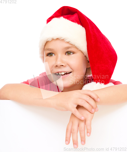 Image of Little girl in santa hat is holding blank board