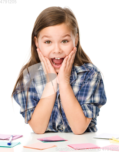 Image of Girl is writing on color stickers using pen