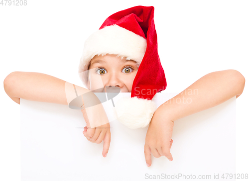 Image of Little girl in santa hat is holding blank board