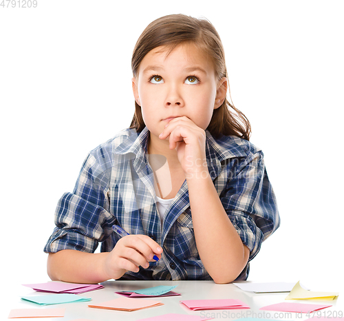 Image of Girl is writing on color stickers using pen