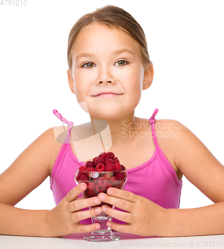 Image of Happy little girl is eating raspberries