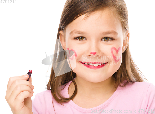 Image of Little girl is applying lipstick on her cheek
