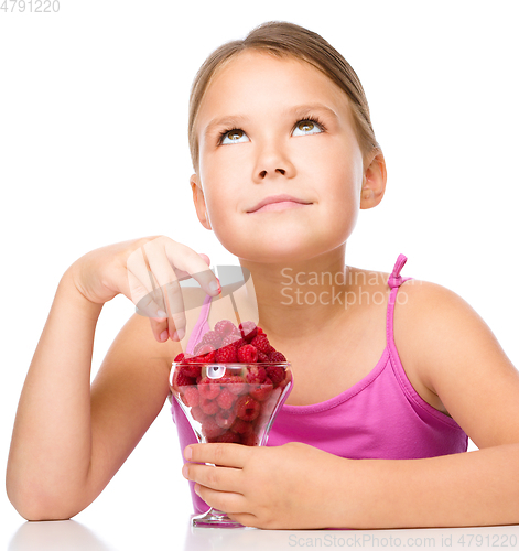 Image of Happy little girl is eating raspberries