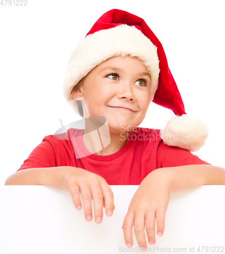 Image of Little girl in santa hat is holding blank board