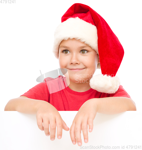 Image of Little girl in santa hat is holding blank board