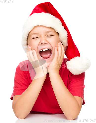 Image of Little girl in santa hat is daydreaming