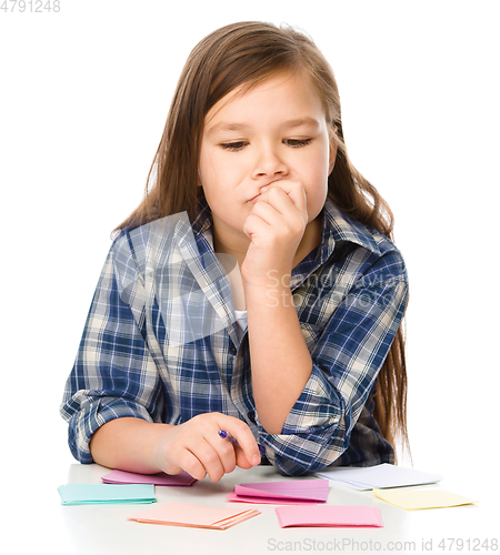 Image of Girl is writing on color stickers using pen