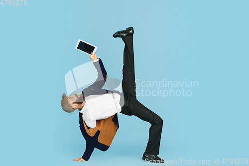 Image of Businessman having fun dancing break dance on blue background at work