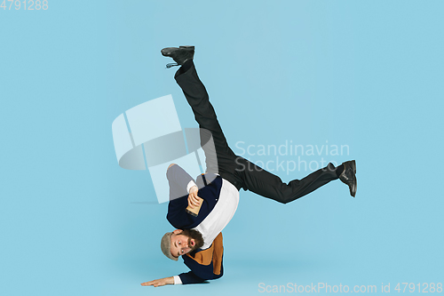 Image of Businessman having fun dancing break dance on blue background at work