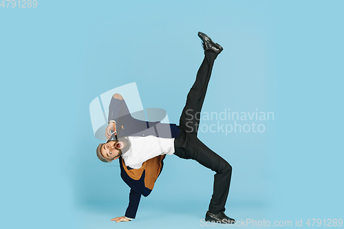 Image of Businessman having fun dancing break dance on blue background at work