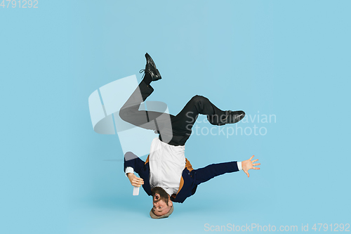 Image of Businessman having fun dancing break dance on blue background at work