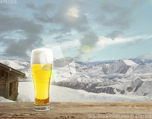 Image of Single light beer in glass and landscape of mountains on background