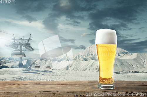 Image of Single light beer in glass and landscape of mountains on background