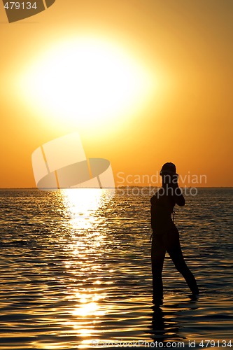 Image of Silhouette of the young woman on a bay on a sunset