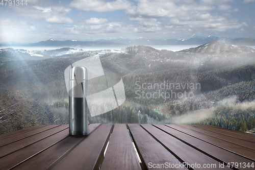 Image of Thermos with tea or coffee and landscape of mountains on background
