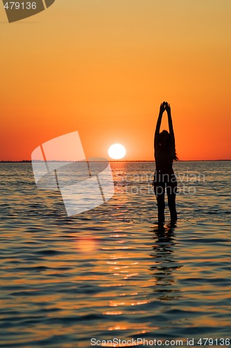 Image of Silhouette of the young woman with hands upwards on a bay on a s