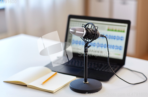Image of microphone, laptop and notebook on table
