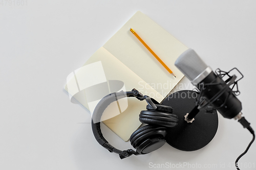 Image of headphones, microphone and notebook with pencil