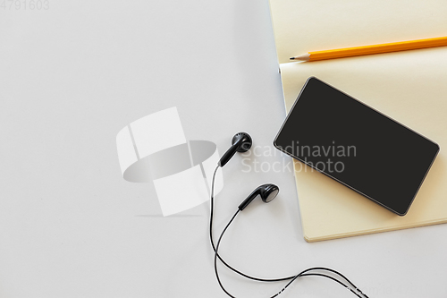 Image of earphones, smartphone and notebook with pencil