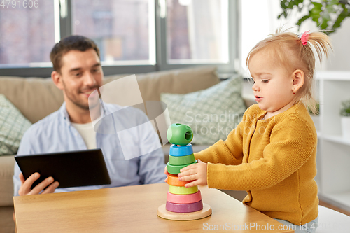Image of father with tablet pc and baby daughter at home
