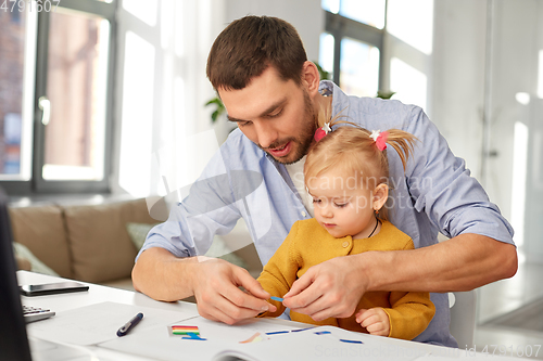 Image of working father with baby daughter at home office