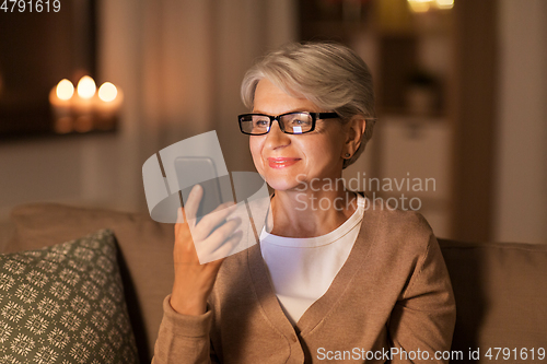 Image of happy senior woman with smartphone at home