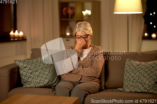 Image of tired senior woman in glasses at home at night