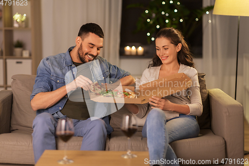 Image of happy couple eating takeaway pizza at home