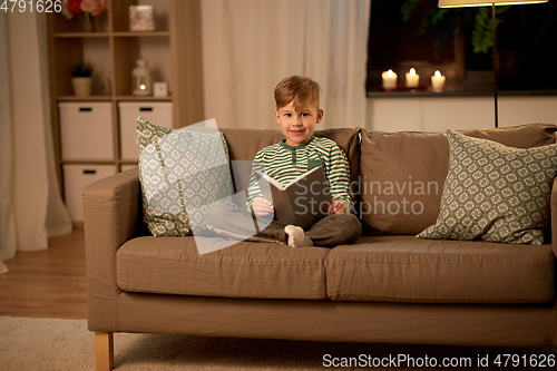 Image of happy little boy reading book at home