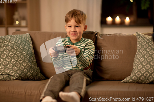 Image of little boy with gamepad playing video game at home