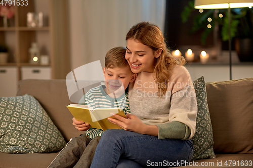 Image of happy mother and son reading book sofa at home