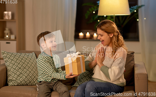 Image of little son giving present to mother at home