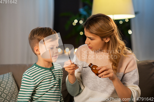 Image of mother giving medication or cough syrup to ill son