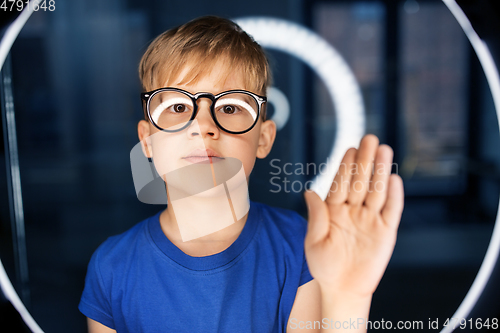 Image of boy in glasses over illumination in dark room