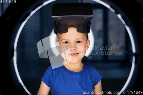 Image of boy in vr glasses over illumination in dark room